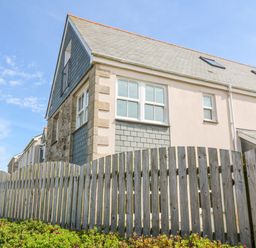 Exterior view of a two story house with a wooden fence and plants in front at Henrys Croft in Lizard