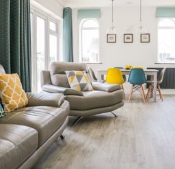 A living room with leather sofas and colorful cushions next to a dining table with mixed color chairs at Senafe in Widemouth Bay