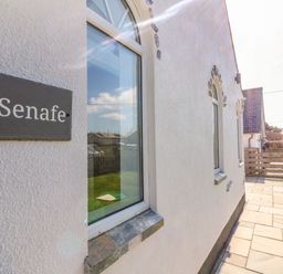 A white building exterior with windows and a black sign that reads Senafe at Senafe in Widemouth Bay