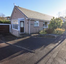 A bungalow with a driveway and garage surrounded by bushes at Fairfell in Keswick