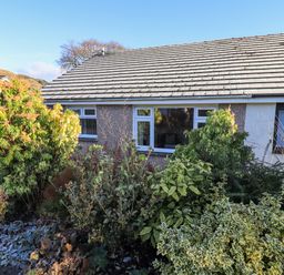 Front view of a single story house with windows and bushes in the garden at Fairfell in Keswick