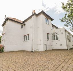 An exterior view of a white two-story house with tiled roof and paved driveway with some plants on the sides at Stakesby House Apartment 3 Whitby
