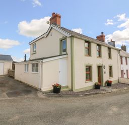 A row of attached houses with flower pots outside on a street at Gwynfa in Capel Iwan near Newcastle Emlyn