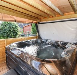 A covered outdoor hot tub with water jets and a garden shed in the background at Phoenix House in Castlemorton