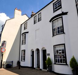 A street view of white buildings with black window frames and doors with plants outside at The Ferryman in Weymouth