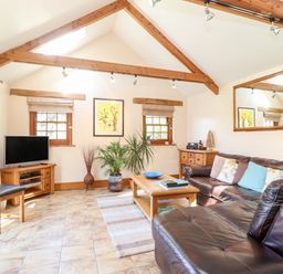 A living room with a leather sofa wooden coffee table television and plants at Valley View in St Martin near Mawgan