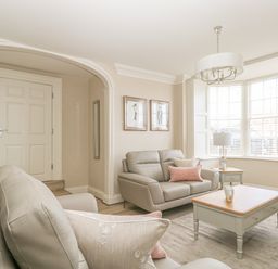 A living room with grey sofas a wooden coffee table a side table with a lamp and large windows at Harbour Watch 2 in Weymouth