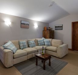 A living room with a beige sectional sofa and blue plaid cushions a wooden coffee table and a wooden cabinet at Riverhouse Lodge in Upwey