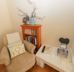 A corner with an armchair next to a wooden bookshelf and a white brick hearth with books at Yr Hen Ardd in Dale near Milford Haven