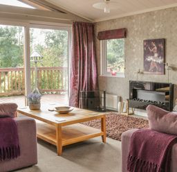 A living room with sofas and a wooden coffee table near sliding glass doors at Bulmer Farm Lodge in Malton
