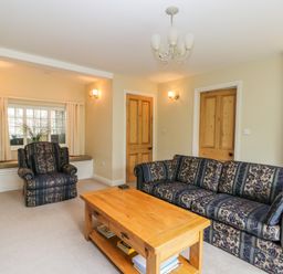 A living room with patterned sofa armchair wooden coffee table and window seat at Stakesby House Apartment 1 in Whitby