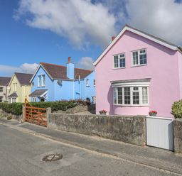 A street with pastel colored houses including a pink house and a blue house at The Pink House in Rhosneigr