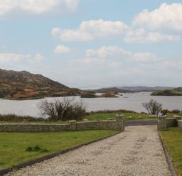 A gravel driveway leading to a lake with hills and small islands in the background at Ranny Roe in Portsalon County Donegal