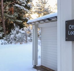 Entry view of Otter Lodge with snow and trees at Otter Lodge in Feshiebridge near Aviemore