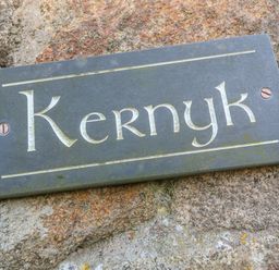 A metal sign with the word Kernyk on a stone wall at Kernyk Rinsey near Porthleven