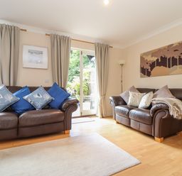 A living room with two leather sofas with cushions and a rug at Deja Blue in Falmouth