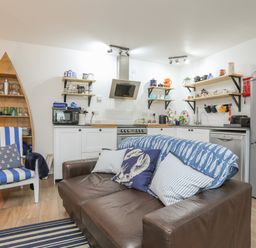 A kitchen and seating area with a brown leather sofa and striped armchair at The Old Boat Store in Morfa Nefyn