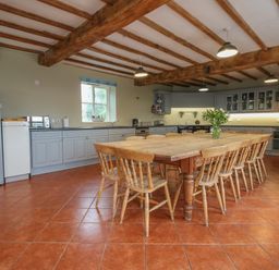 A kitchen with wooden dining table and chairs under exposed wooden beams at Hunters Moon in Tenbury Wells