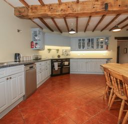 A kitchen with cabinets appliances and a wooden dining table with chairs at Hunters Moon in Tenbury Wells