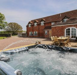 A hot tub and outdoor seating area at Hunters Moon Tenbury Wells
