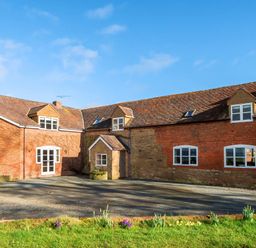 A brick house with multiple windows and a gravel driveway at The Chestnuts in Tenbury Wells