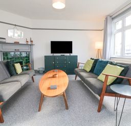 A living room with two gray sofas with cushions a wooden coffee table a gray fireplace and a television on a cabinet at Chilton in Bude
