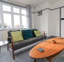 A living room with a gray sofa with green and blue cushions a wooden coffee table and side tables at Chilton in Bude