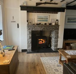 A living room with a fireplace and a television at Tyddyn Serri in Rhosneigr