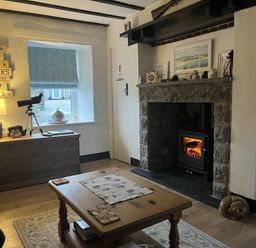 A living room with a fireplace and telescope at Tyddyn Serri in Rhosneigr