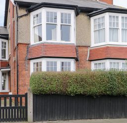 Exterior view of a two story semi detached house with bay windows hedge and black wooden fence at Beach House in Bridlington