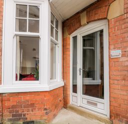 A brick exterior wall with a white framed bay window and a white door with glass panels at Beach House in Bridlington