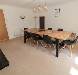 A dining room with a wooden table and black chairs at Changing Tide in Beadnell