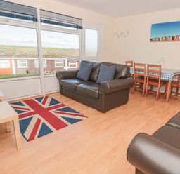 A living room with two leather sofas a table with four wooden chairs and a rug with a union jack pattern at 304 Norton Park in Dartmouth