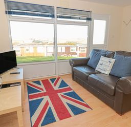 A living room with a leather sofa a union jack rug a television and a model sailboat at 304 Norton Park in Dartmouth