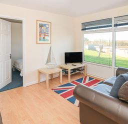 A living room with brown leather sofas a tv on a wooden table and a rug with a union jack design at 304 Norton Park Dartmouth