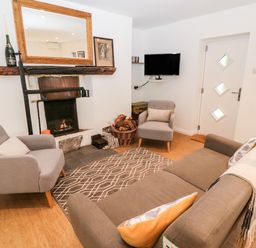 A living room with armchairs sofa fireplace and a wall-mounted television at Kealduff Lower in Glenbeigh County Kerry