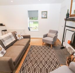 A living room with a sofa armchair patterned rug and fireplace at Kealduff Lower in Glenbeigh County Kerry