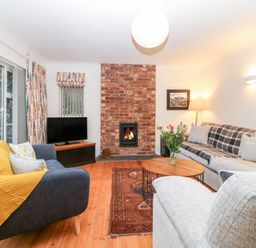 A living room with a brick fireplace a television two sofas a wooden coffee table and a rug at Casalmare in Exmouth