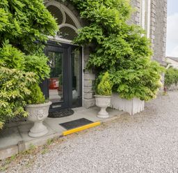 A black door entrance with two stone planters and green foliage around at Capel Mawr Basement 19 in Llanrug