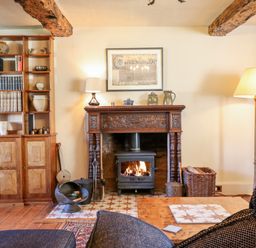 A living room with a wood burning stove fireplace wooden bookshelf and a floor lamp at Aluric's Hall in Porlock