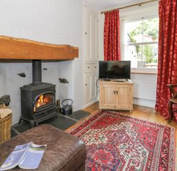 A living room with a stove and wooden furniture at Sygun View Beddgelert