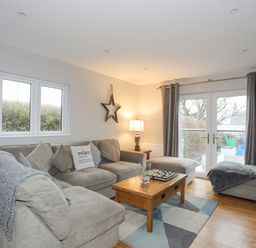 A living room with a grey sectional sofa and wooden coffee table at Laneton in Rhosneigr