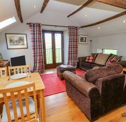 A sitting room with two sofas a wooden dining table with chairs and plaid curtains at Field Barn in Alston