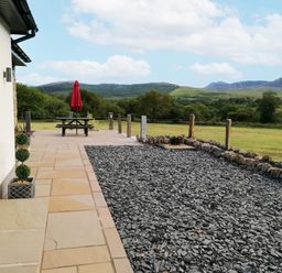 A patio with a picnic table and an umbrella at Cartref Trawsfynydd