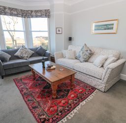 A living room with two sofas a wooden coffee table and a red patterned rug at Whinstones at 4 The Villas in Embleton