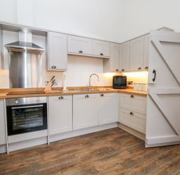 A kitchen with grey cabinets wooden countertops stainless steel oven and hood with a wooden floor at Lakeside Village Lodges & The Potting Shed in Capesthorne near Macclesfield