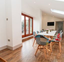 A dining room with a long white table surrounded by colorful chairs and potted plants on the table at Lakeside Village Lodges & The Potting Shed in Capesthorne near Macclesfield
