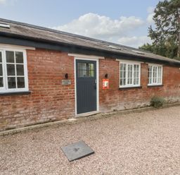 A brick building with white windows and a blue door labeled potting shed at Lakeside Village Lodges & The Potting Shed in Capesthorne near Macclesfield