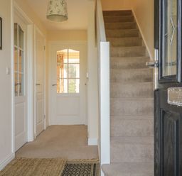 A hallway with a carpeted staircase and white doors at Rowan Cottage in St Bees