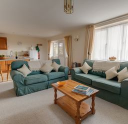 A living room with two green sofas a wooden coffee table and an open kitchen at Willow Barn in Cucklington near Wincanton